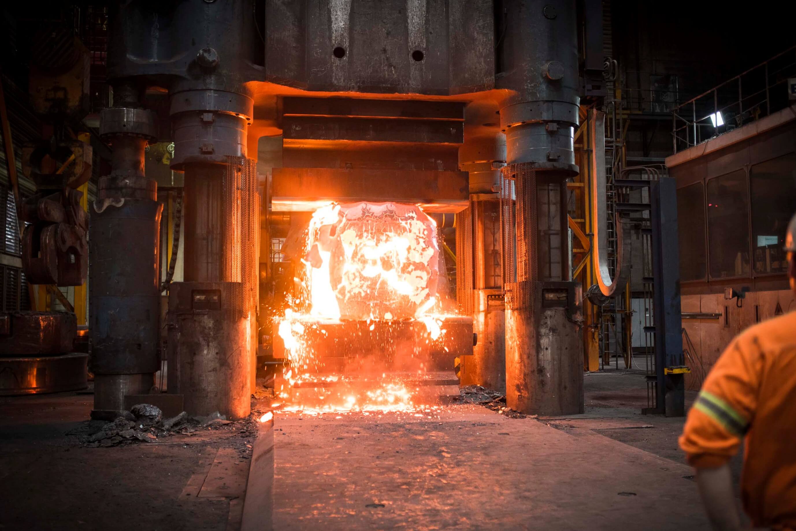 steel block glowing red-hot in a forging press